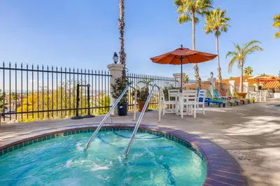 a swimming pool with an umbrella and a table and chairs at Best Western Plus Hacienda Hotel Old Town in San Diego