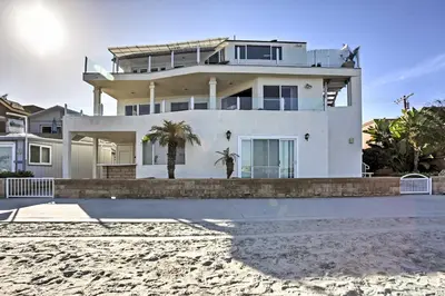 a white house with a palm tree in front of it at Beachfront San Diego Condo with Patio on the Bay! in San Diego