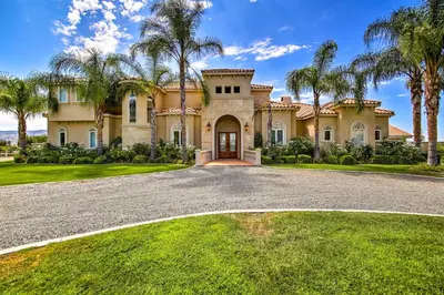 a house with palm trees in front of a driveway at Luxe Wine Country Estate with Orchard-Facing Balcony in Temecula