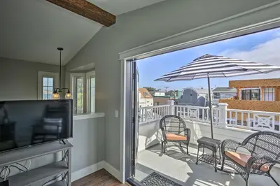 a living room with a tv and a balcony with chairs and an umbrella at San Diego Home - Walk to Sail Bay and Mission Beach! in San Diego