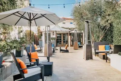 an outdoor patio with chairs and an umbrella at Hotel Marisol Coronado in San Diego