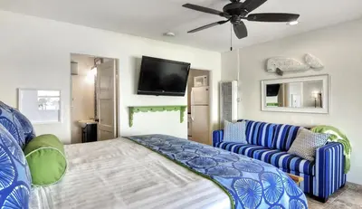 a bedroom with a bed and a couch and a flat screen tv at Beachcomber Inn in San Clemente