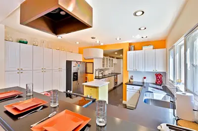 a large kitchen with white cabinets and orange walls at Casa Dolce in San Diego