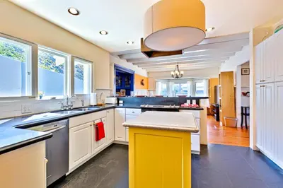 a large kitchen with yellow and white cabinets and windows at Casa Dolce in San Diego