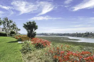 a bench sitting on the grass next to a river at 1000#3 Renovated Home by Beach & Sand - AC & More! in Newport Beach