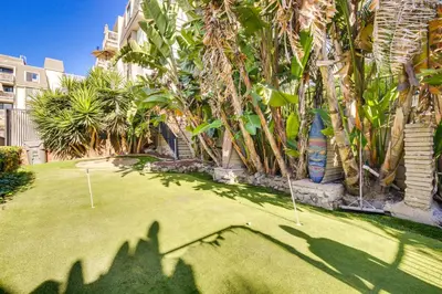 a yard with palm trees and two putting greens at Tropical Oceanside Home with Deck, Walk to Beach in Oceanside