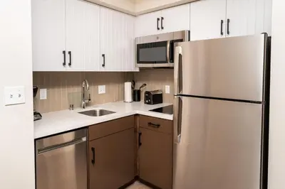 a kitchen with white cabinets and a stainless steel refrigerator at Staybridge Suites - Temecula - Wine Country by IHG in Temecula