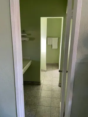 a bathroom with green walls and a tiled hallway at RAMONA MOTEL in Hemet