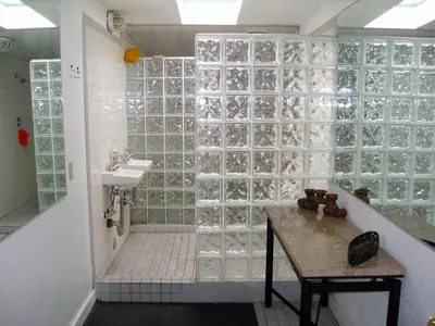 a bathroom with a sink and a shower with glass block walls at RK Hostel in San Diego