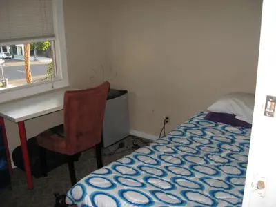 a bedroom with a bed and a desk and a window at RK Hostel in San Diego
