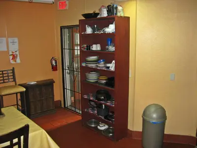a kitchen with a shelf with plates and dishes at RK Hostel in San Diego