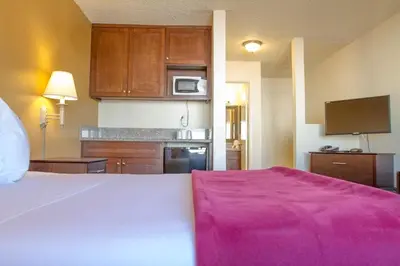 a bedroom with a large bed with a pink blanket at California Suites Hotel in San Diego