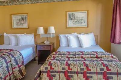 a hotel room with two beds and a table with two lamps at California Suites Hotel in San Diego