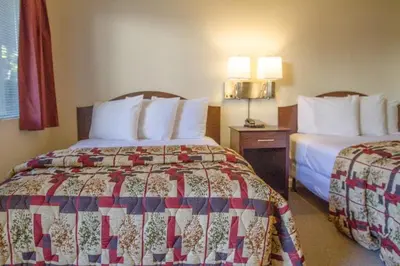 a hotel room with two beds with white pillows at California Suites Hotel in San Diego