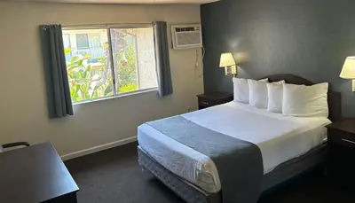 a hotel room with a bed and a window at California Suites Hotel in San Diego