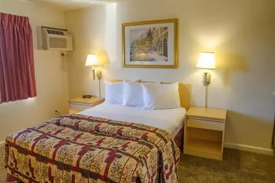a hotel room with a large bed and two night stands at California Suites Hotel in San Diego