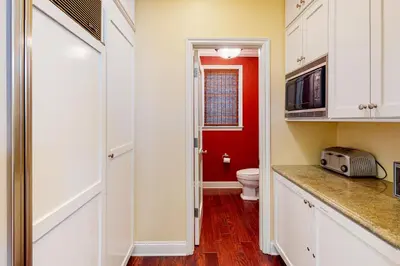 a bathroom with a toilet and a red wall at Sycamore Beach Retreat in Carlsbad