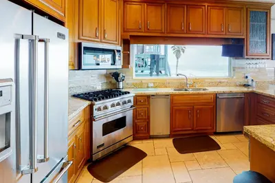 a kitchen with wooden cabinets and a stove and a window at Luxury Oceanfront Home - Lower in Oceanside