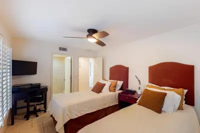 a bedroom with two beds and a desk with a piano at Luxury Oceanfront Home - Lower in Oceanside