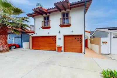 a white house with a brown garage door at Luxury Oceanfront Home - Lower in Oceanside