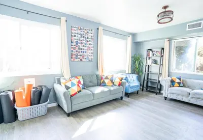 a living room with two couches and two windows at California Dreams Hostel - Ocean Beach in San Diego