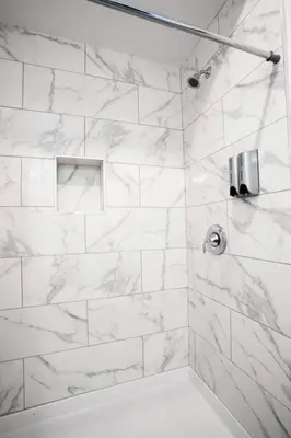 a bathroom with a shower with white marble tiles at Centrally Located Cozy Studio Apartment in SD in San Diego