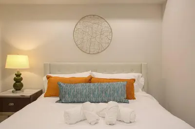 a bedroom with a white bed with orange and blue pillows at 1-Bedroom with Cali King Size Bed in San Diego in San Diego
