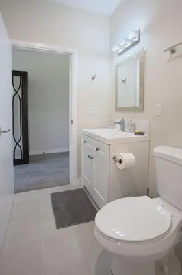 a white bathroom with a toilet and a sink at Awesome Balboa and Downtown View with Cozy Patio in San Diego