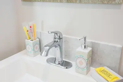 a bathroom sink with a faucet and toothbrushes at Luxurious Furnished Studio w Full Kitchen in SD in San Diego