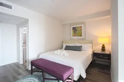 a white bed with a purple bench in a bedroom at One Bedroom Apartment with SD Downtown View in San Diego