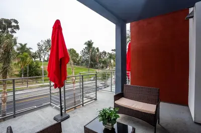 a patio with a red umbrella and a table and chairs at Studio with Large Balcony- San Diego Gateway in San Diego