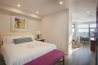 a bedroom with a large white bed with a purple bench at The Most Beautiful Bay View from 1 Bedroom Apt in San Diego