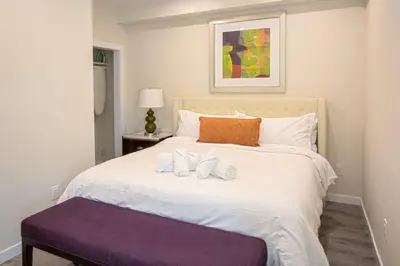 a bedroom with a large white bed with a purple seat at Luxurious One Bedroom Suite with Balboa Park View in San Diego