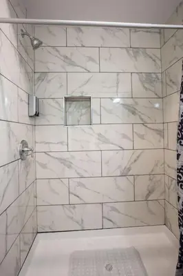 a bathroom with a shower with white marble tiles at Next to San Diego Downtown - Cali King Size Studio in San Diego