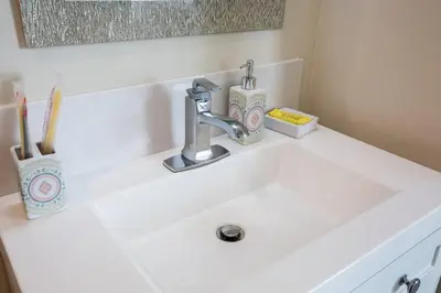 a bathroom sink with a faucet and two tooth brushes at Modern, Luxurious and Prime location All in One in San Diego