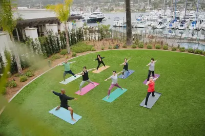 a group of people doing yoga on the grass at Kona Kai Resort & Spa, a Noble House Resort in San Diego