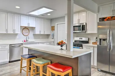 a kitchen with white cabinets and a counter with stools at San Marcos Home with Patio and Grill - Walk to Lake! in San Marcos