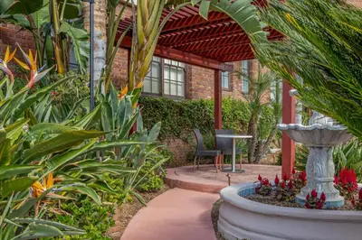 a garden with a fountain and a chair in front of a building at Inn at the Park in San Diego