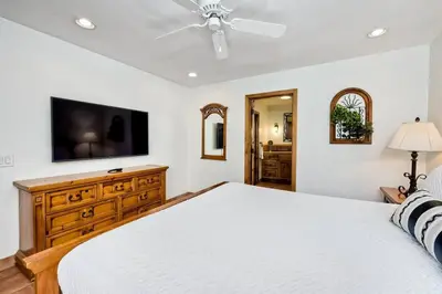 a bedroom with a white bed and a flat screen tv at Great Group Retreat! Hacienda Decor, Spacious Floor Plan, Private Backyard in Carlsbad