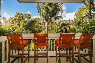 three chairs on a porch with palm trees at C109 - Sea Breeze - On-the-Sand in Oceanside
