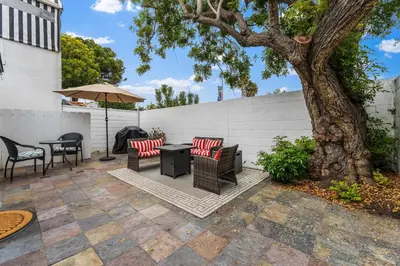 a patio with chairs and an umbrella and a tree at La Jolla Beach Casita in San Diego