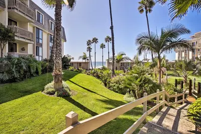 a resort with palm trees and a white fence at Charming Oceanside Condo with Beach and Pool Access! in Oceanside