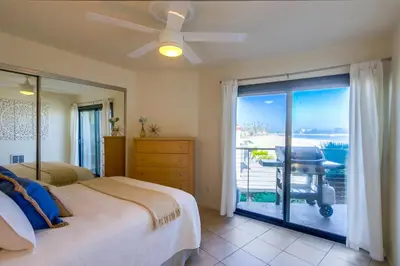 a bedroom with a bed and a balcony with a desk at Cohasset Getaway Unit #3 in San Diego
