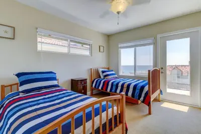 a bedroom with two beds and two windows at The Bridge At South Oceanside is the Perfect Family Beach House now with AC in Oceanside