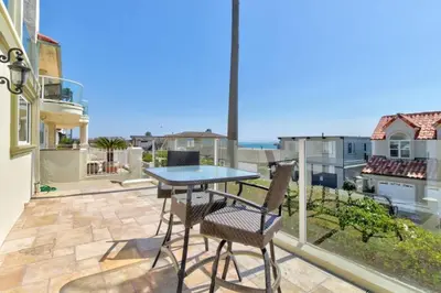a patio with a table and chairs on a balcony at The Bridge At South Oceanside is the Perfect Family Beach House now with AC in Oceanside