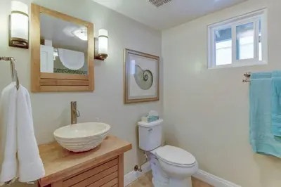 a bathroom with a sink and a toilet and a mirror at The Bridge At South Oceanside is the Perfect Family Beach House now with AC in Oceanside