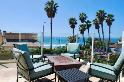a patio with chairs and a table and the ocean at The Bridge At South Oceanside is the Perfect Family Beach House now with AC in Oceanside