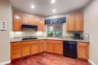 a kitchen with wooden cabinets and a black dishwasher at Ocean Pointe Lagoon 107 - 30 Night Minimum in Carlsbad