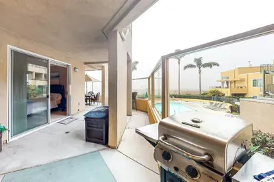 an outdoor patio with a grill and a pool at Ocean Pointe Lagoon 107 - 30 Night Minimum in Carlsbad