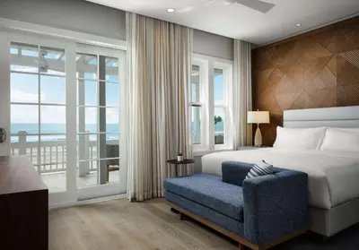a bedroom with a bed and a chair and a window at Shore House at The Del, LXR Hotels & Resorts in San Diego